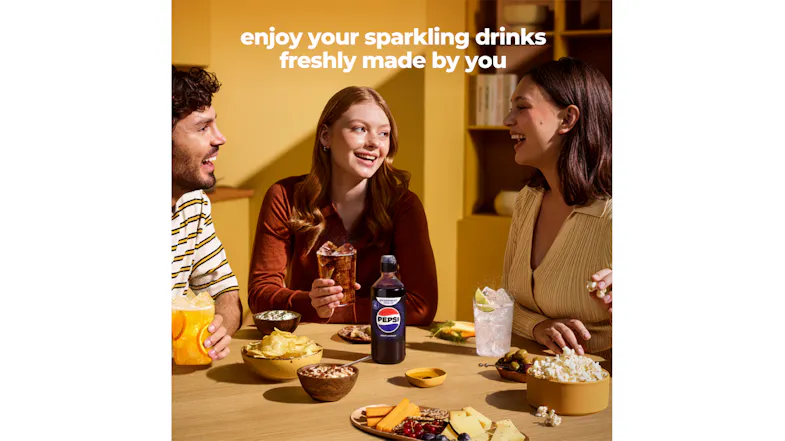 People seated around a dining table with sparkling drinks, snacks, and a Pepsi syrup bottle People seated around a dining table with sparkling drinks, snacks, and a Pepsi syrup bottle