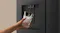 Close-up of a black Haier 500 Series refrigerator dispensing chilled water into an ice-filled glass Close-up of a black Haier 500 Series refrigerator dispensing chilled water into an ice-filled glass