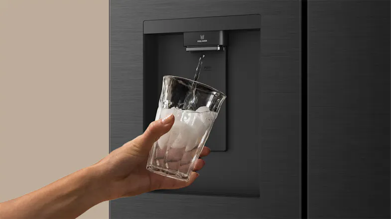 Close-up of a black Haier 500 Series refrigerator dispensing chilled water into an ice-filled glass Close-up of a black Haier 500 Series refrigerator dispensing chilled water into an ice-filled glass