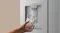 Silver refrigerator water dispenser dispensing chilled water into a clear glass with ice Silver refrigerator water dispenser dispensing chilled water into a clear glass with ice