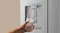 Close-up of a silver refrigerator water dispenser dispensing water into a clear glass with ice Close-up of a silver refrigerator water dispenser dispensing water into a clear glass with ice