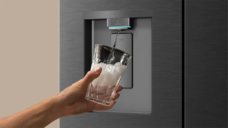 Close-up of a black refrigerator water dispenser filling an ice-filled glass with chilled water Close-up of a black refrigerator water dispenser filling an ice-filled glass with chilled water
