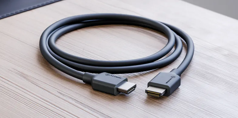 Angled close-up of a black HDMI cable with metal connector tips on a wood-grain surface Angled close-up of a black HDMI cable with metal connector tips on a wood-grain surface