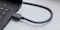 Angled close-up of a black HDMI cable connected to a laptop HDMI port, featuring a flexible looped cable design Angled close-up of a black HDMI cable connected to a laptop HDMI port, featuring a flexible looped cable design