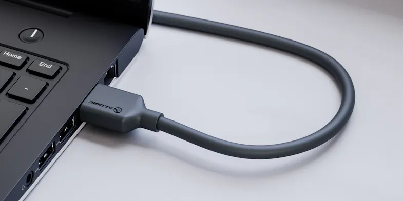 Angled close-up of a black HDMI cable connected to a laptop HDMI port, featuring a flexible looped cable design Angled close-up of a black HDMI cable connected to a laptop HDMI port, featuring a flexible looped cable design