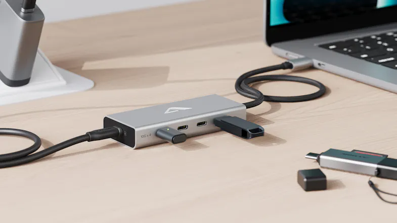 Space grey USB-C hub connected to a laptop on a desk, with multiple USB-C devices and a flash drive attached Space grey USB-C hub connected to a laptop on a desk, with multiple USB-C devices and a flash drive attached