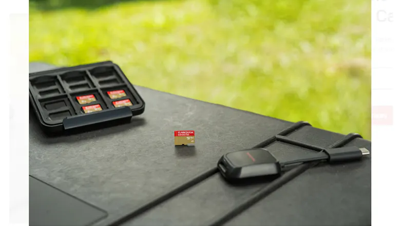 A SanDisk Extreme GO microSD card, complete with a card case and a USB-C card reader, resting on a black outdoor surface A SanDisk Extreme GO microSD card, complete with a card case and a USB-C card reader, resting on a black outdoor surface
