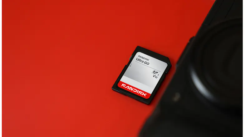 Close-up angled view of a SanDisk Ultra GO SDHC UHS-I memory card next to a black camera Close-up angled view of a SanDisk Ultra GO SDHC UHS-I memory card next to a black camera