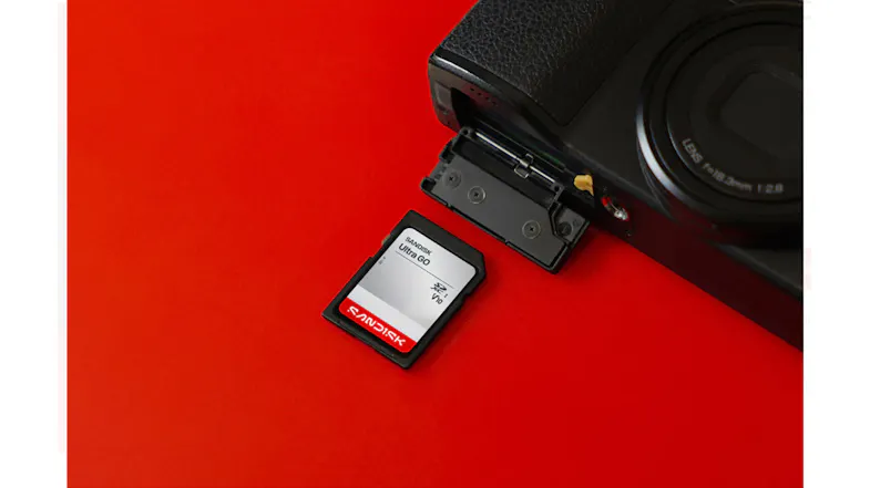 Angled view of a SanDisk Ultra GO SDHC UHS-I memory card beside an open camera card slot Angled view of a SanDisk Ultra GO SDHC UHS-I memory card beside an open camera card slot