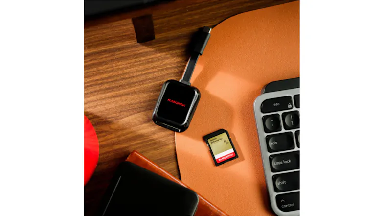 Angled top view of a SanDisk Extreme GO SD card and a black card reader beside a laptop keyboard on a desk Angled top view of a SanDisk Extreme GO SD card and a black card reader beside a laptop keyboard on a desk