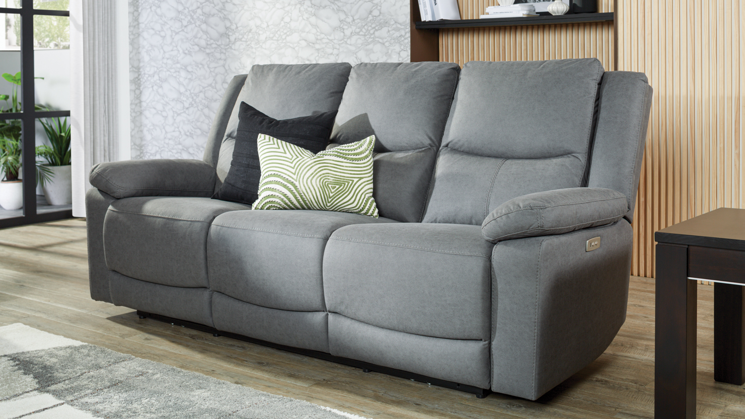 Grey fabric 3-seater electric recliner sofa with two decorative pillows in a modern living room