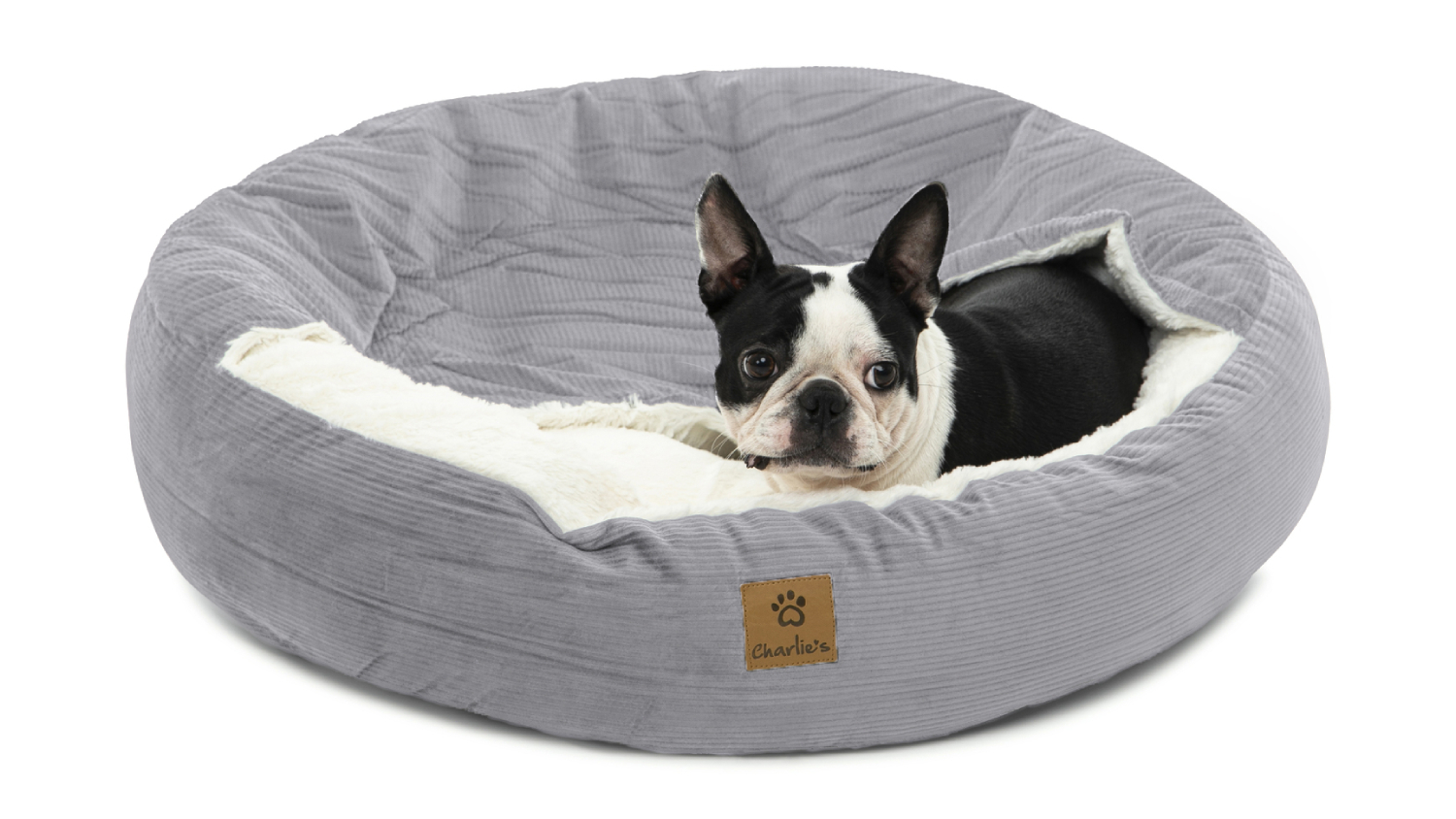 A dog resting on the corduroy pet bed.