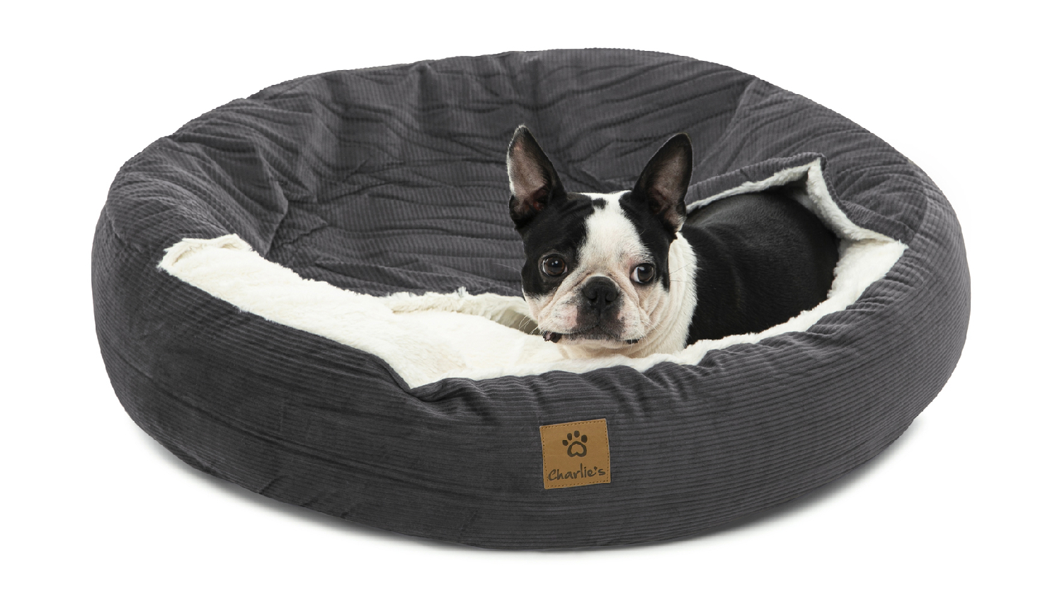 A dog resting on the corduroy pet bed.