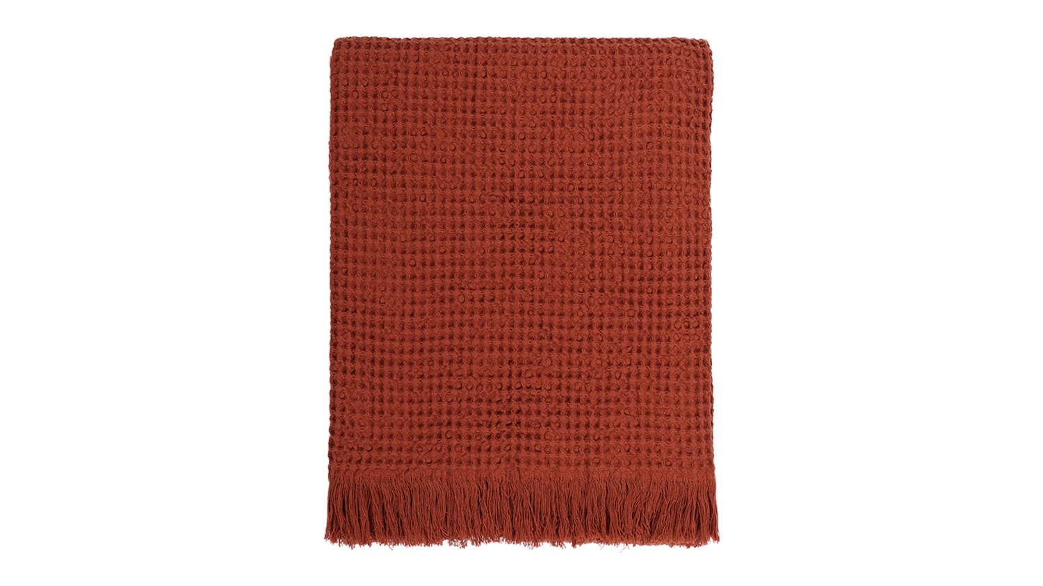 A Celine brick-coloured waffle weave throw blanket neatly folded, featuring fringed edges