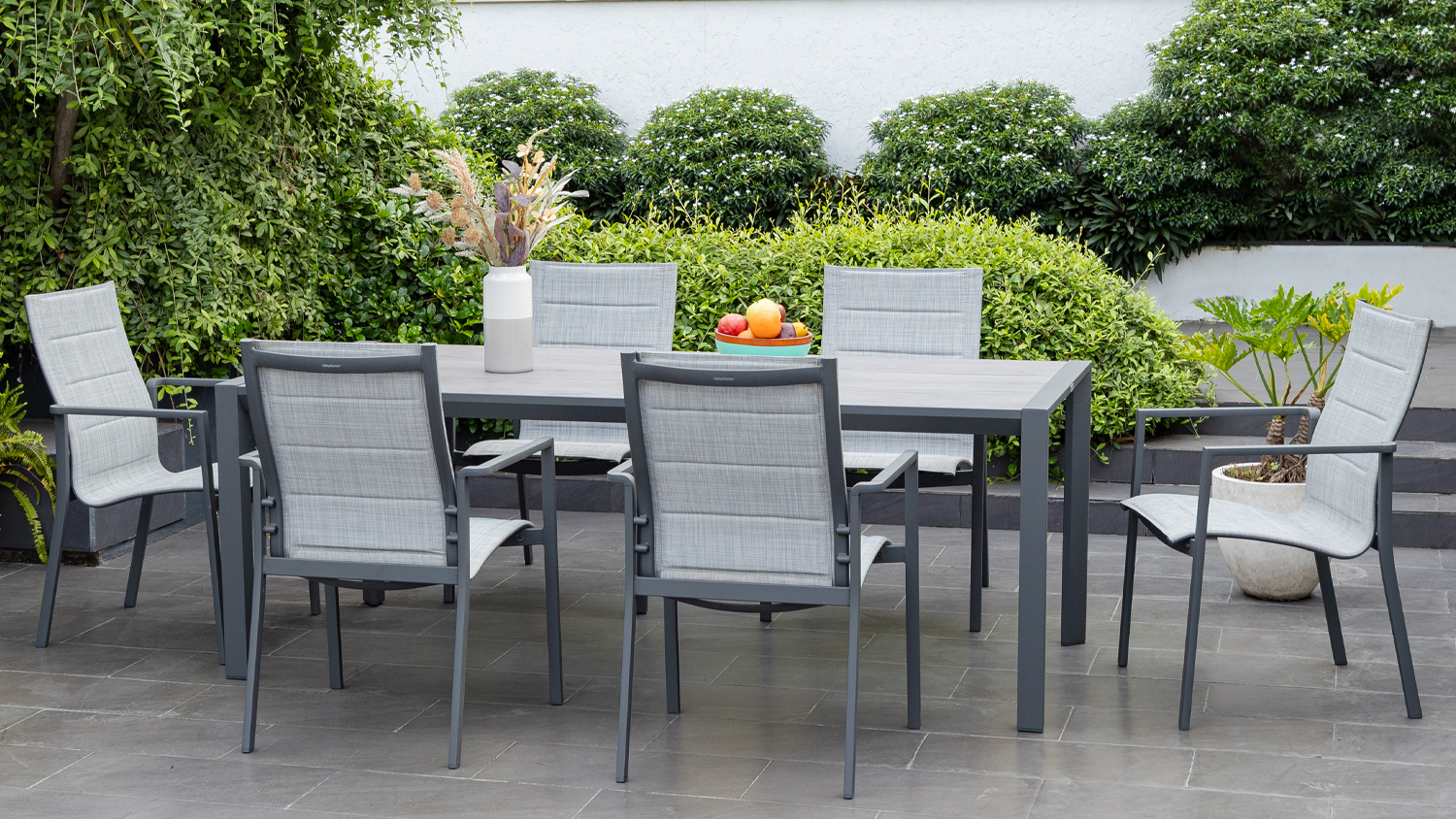 A 7-piece outdoor dining set in a lush garden patio.
