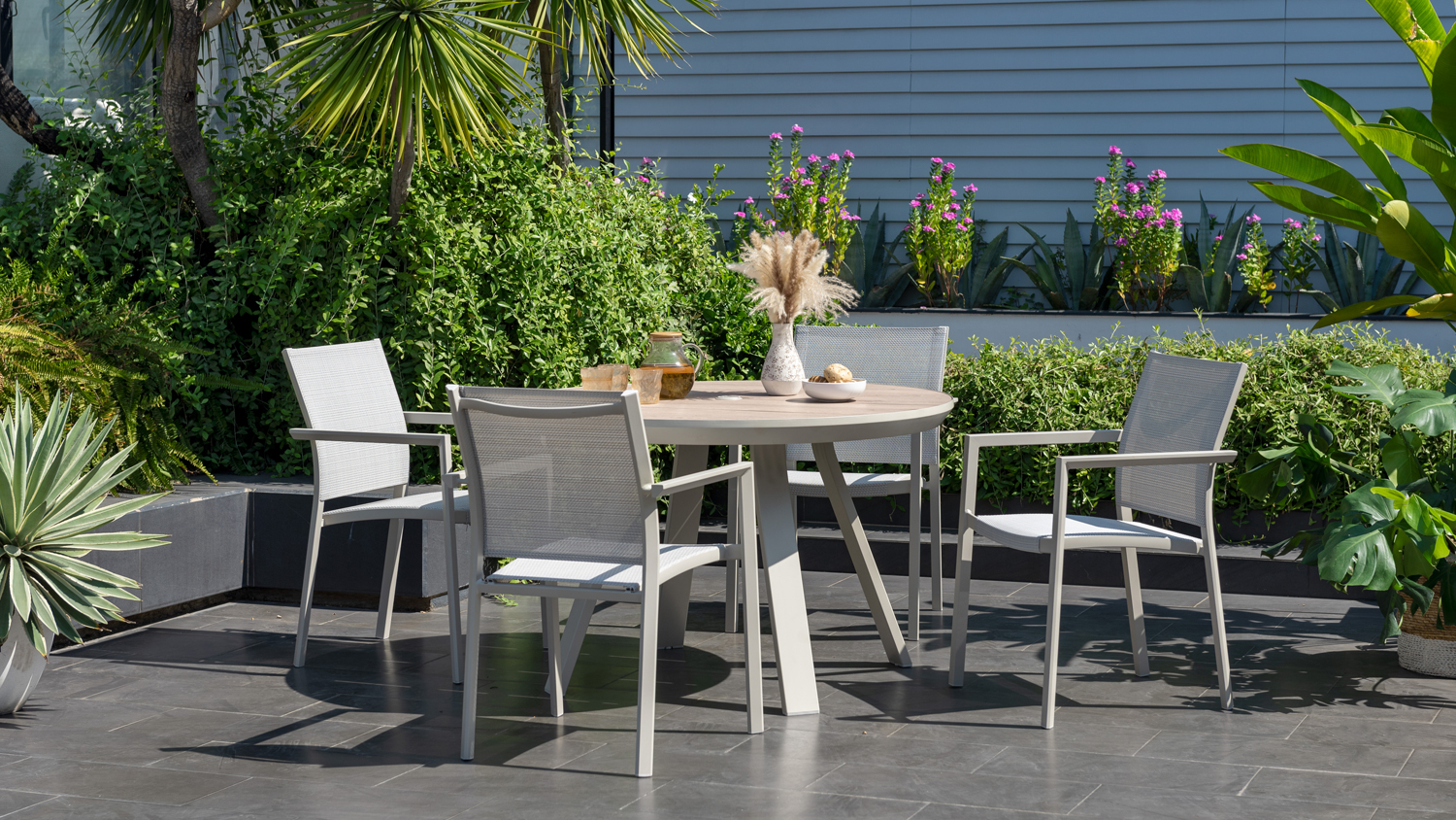 A 5-piece outdoor dining set on a patio surrounded by plants.