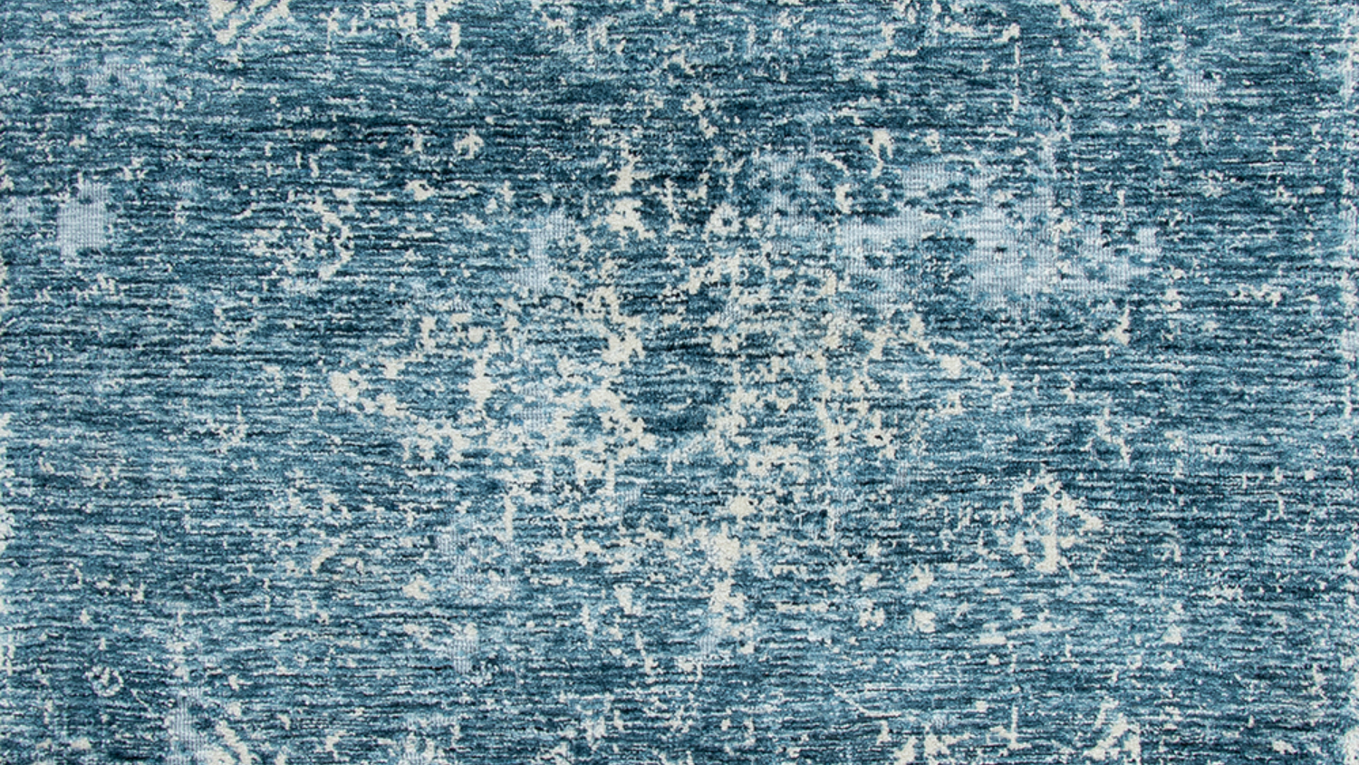 A flat-lay view of a faded-style rug in shades of blue.
