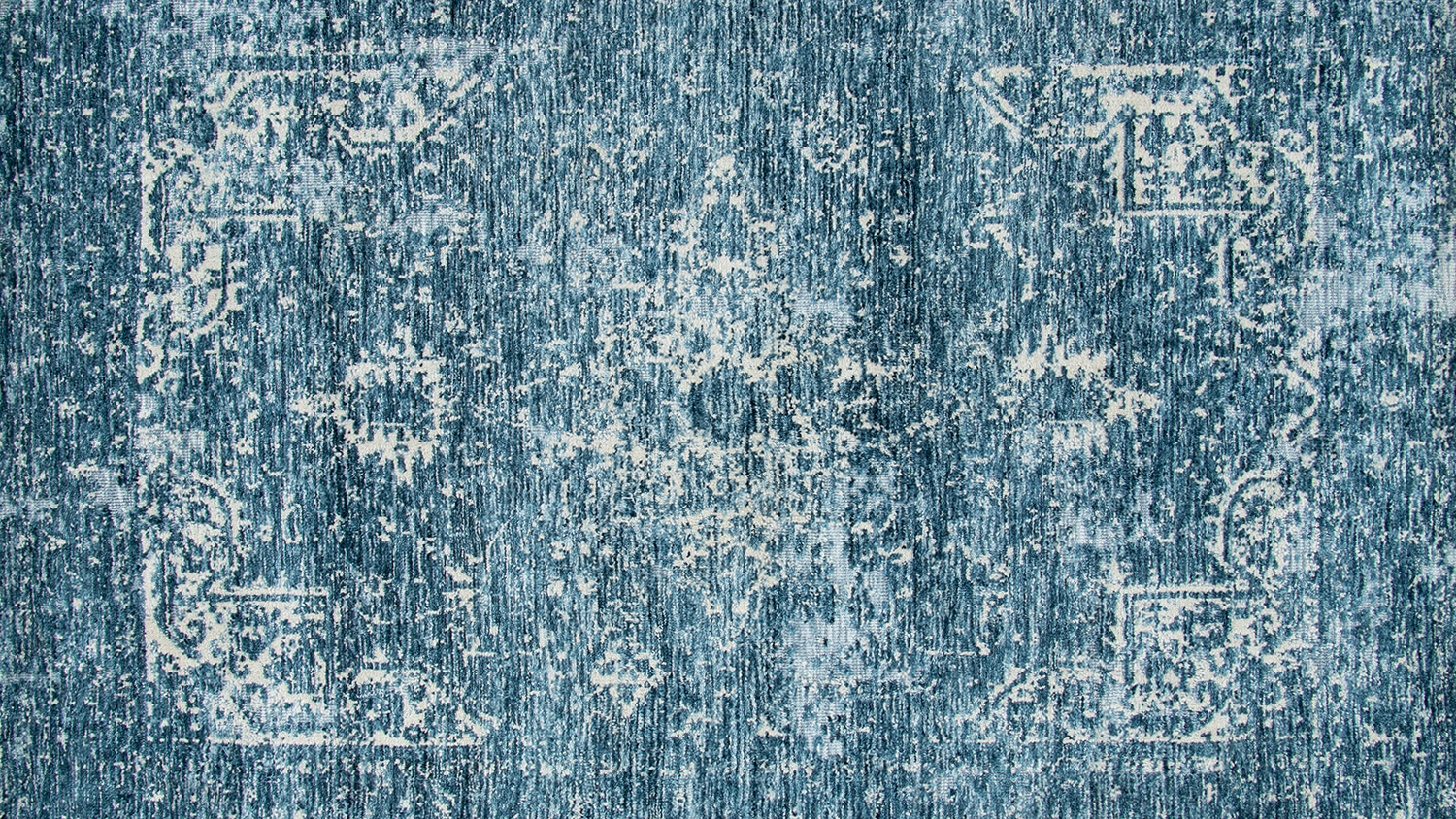 An overhead shot of a blue-toned rug with a distressed finish.