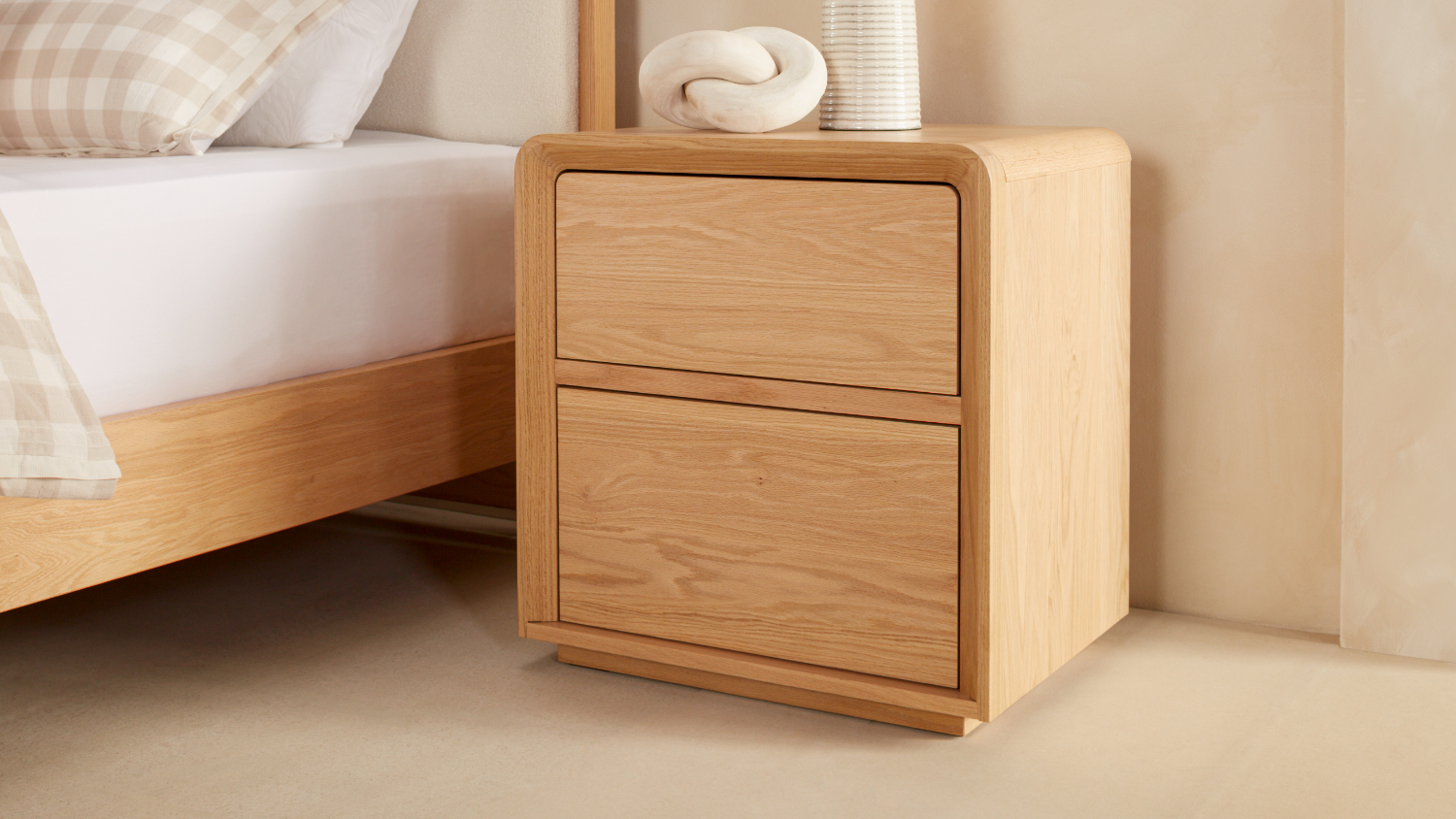 A large wooden bedside table with closed drawers.