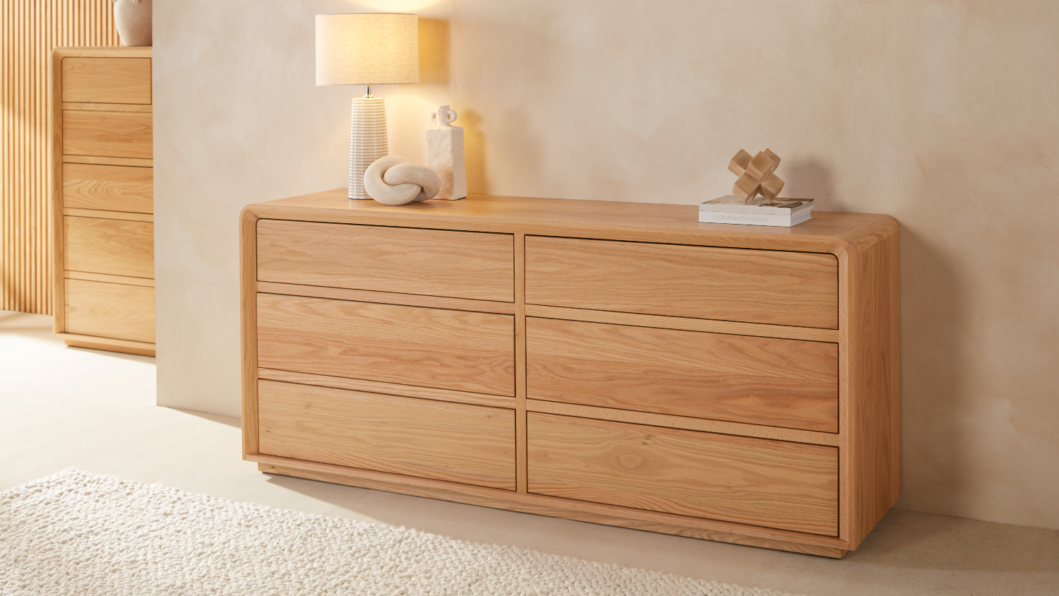 A  large 6-drawer lowboy dresser with a lamp and decor on its top.