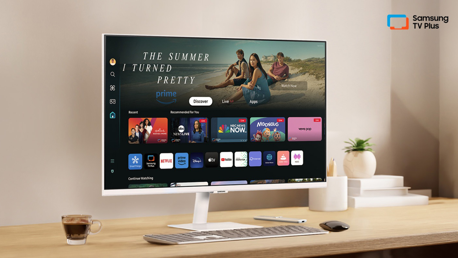 A large monitor in a home office setting with a keyboard on a desk.