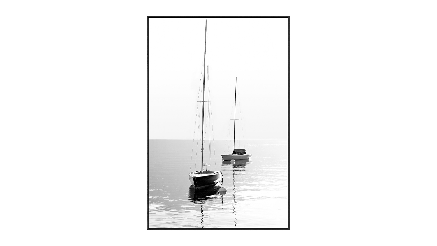 A black and white framed artwork of two sailboats drifting on calm water