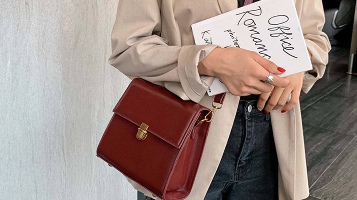 A maroon leather crossbody bag with a gold buckle and an adjustable strap