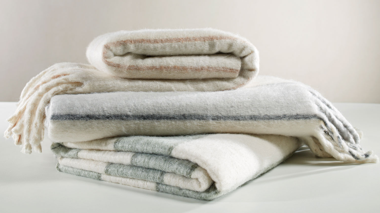 Willow Throw by L'Avenue, pile of 3 throws, soft with wide line pattern in neutral tones