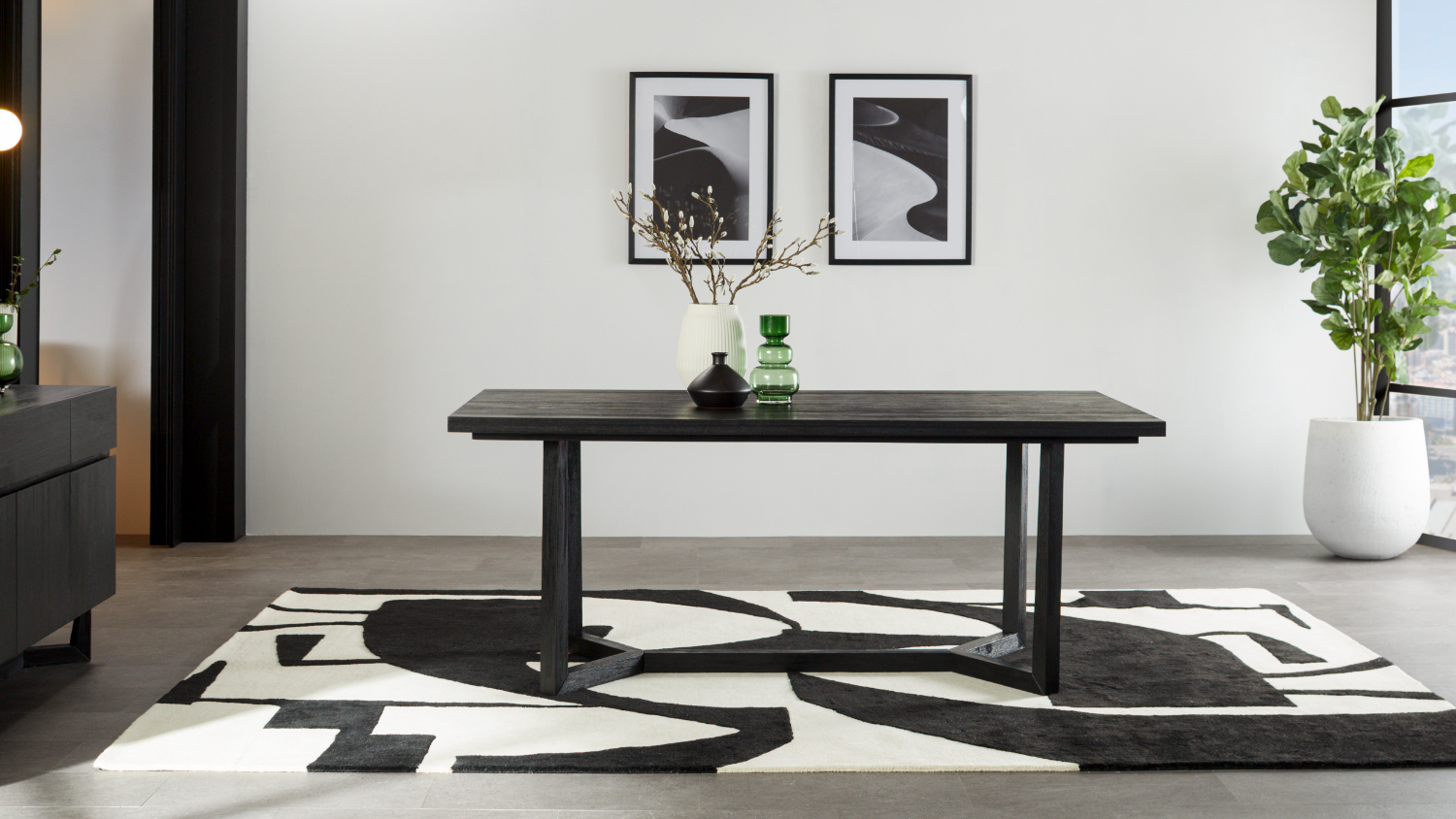 Modern dining room featuring a black rectangular table on a black and white abstract rug