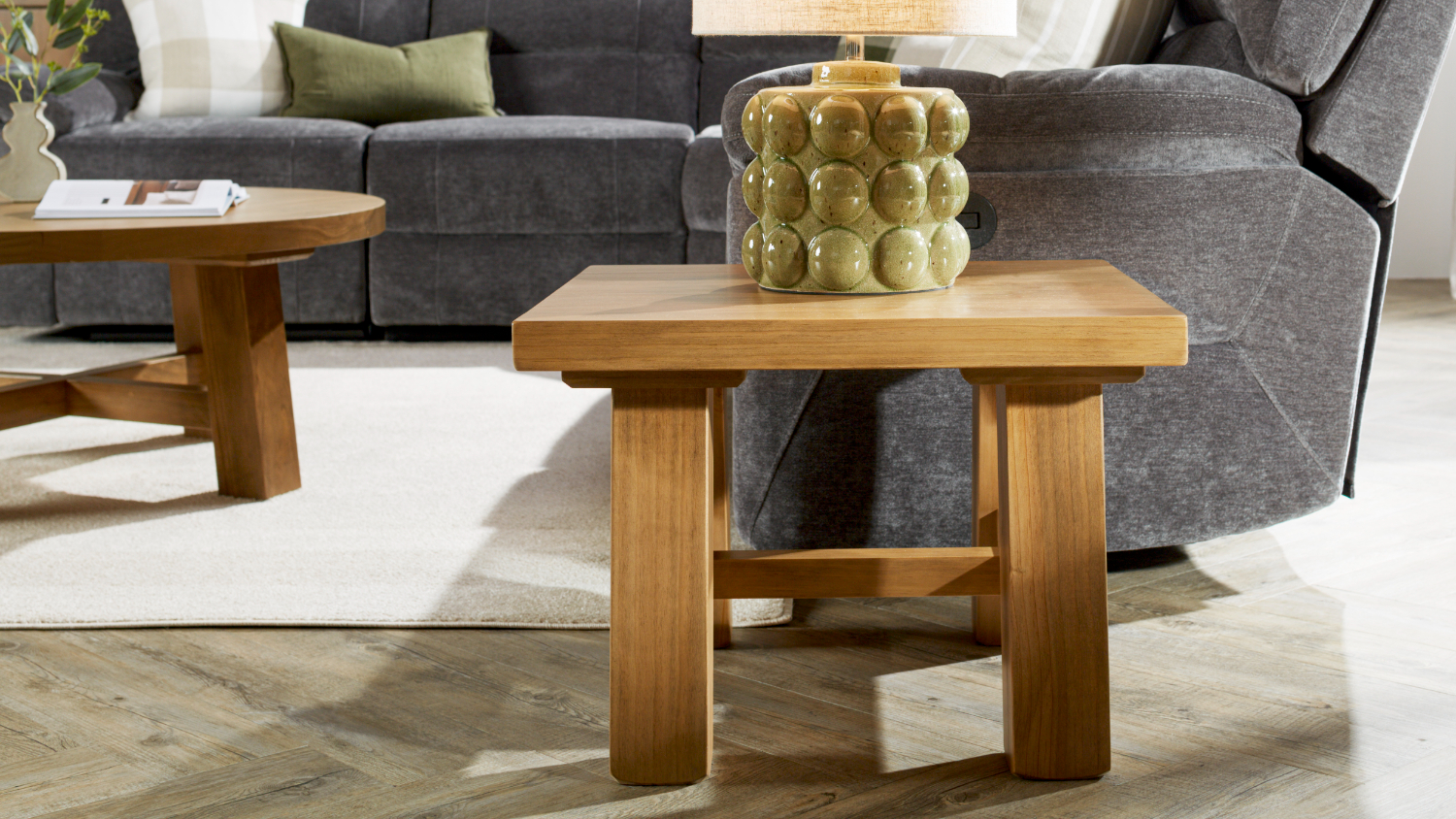 A view of a modern living room with the lamp table positioned beside a grey sofa