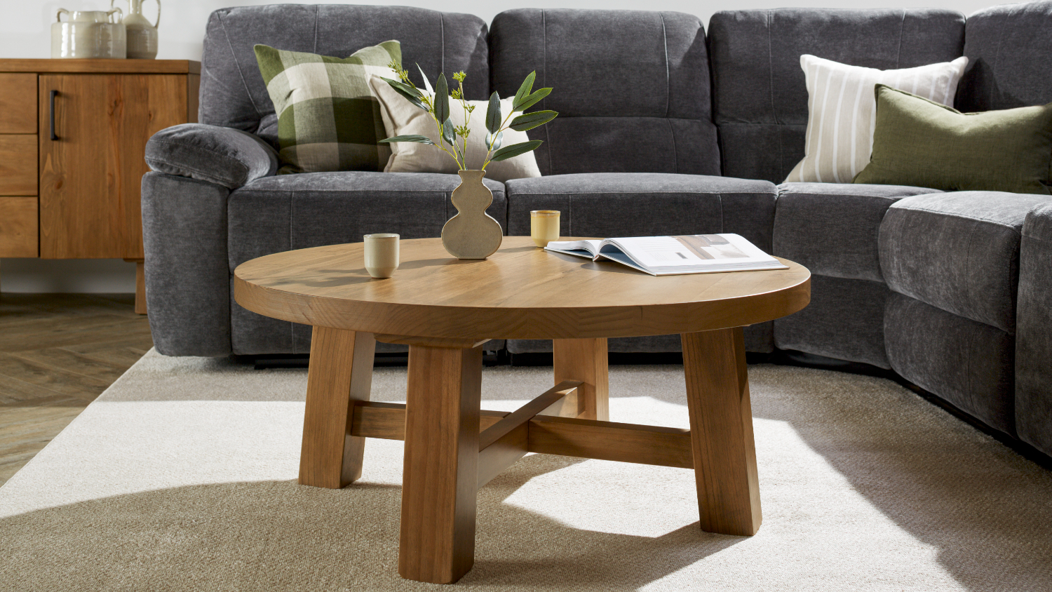 A view of a modern living room with the round coffee table displayed beautifully over a white rug
