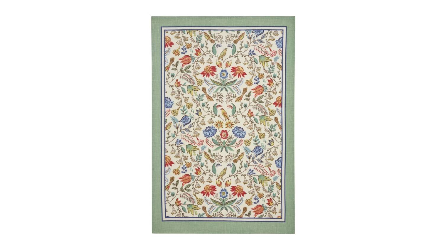 Cotton tea towel with a green border and intricate floral patterns in red, blue, and green on a cream background