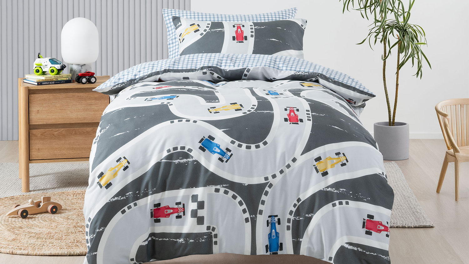A speed racer duvet cover set in a cosy room, showing a race track with red, yellow and blue race cars