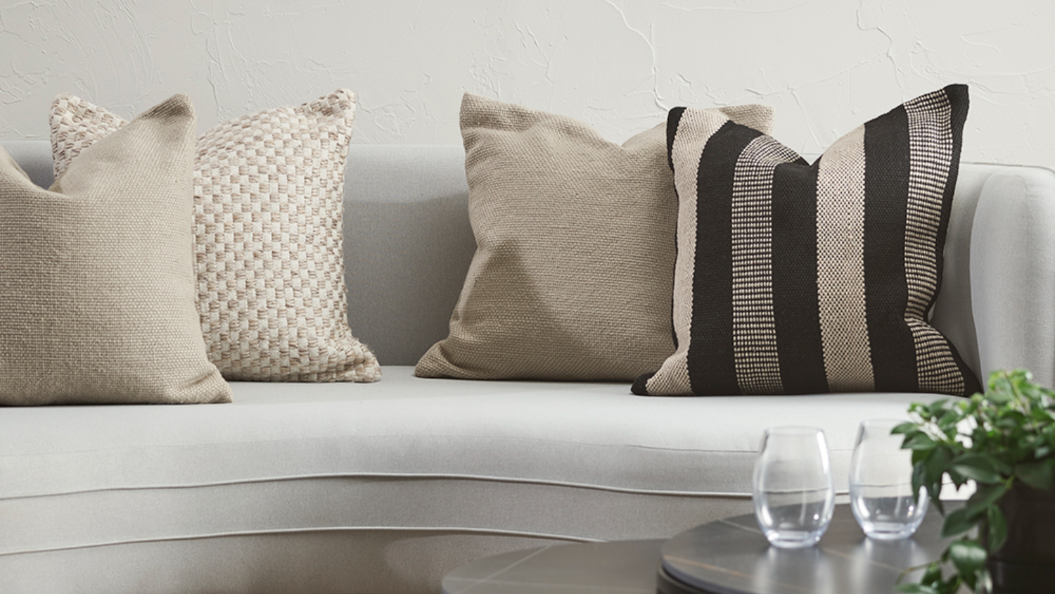 White sofa with four cushions including striped patterned and beige toned in a living room setting.