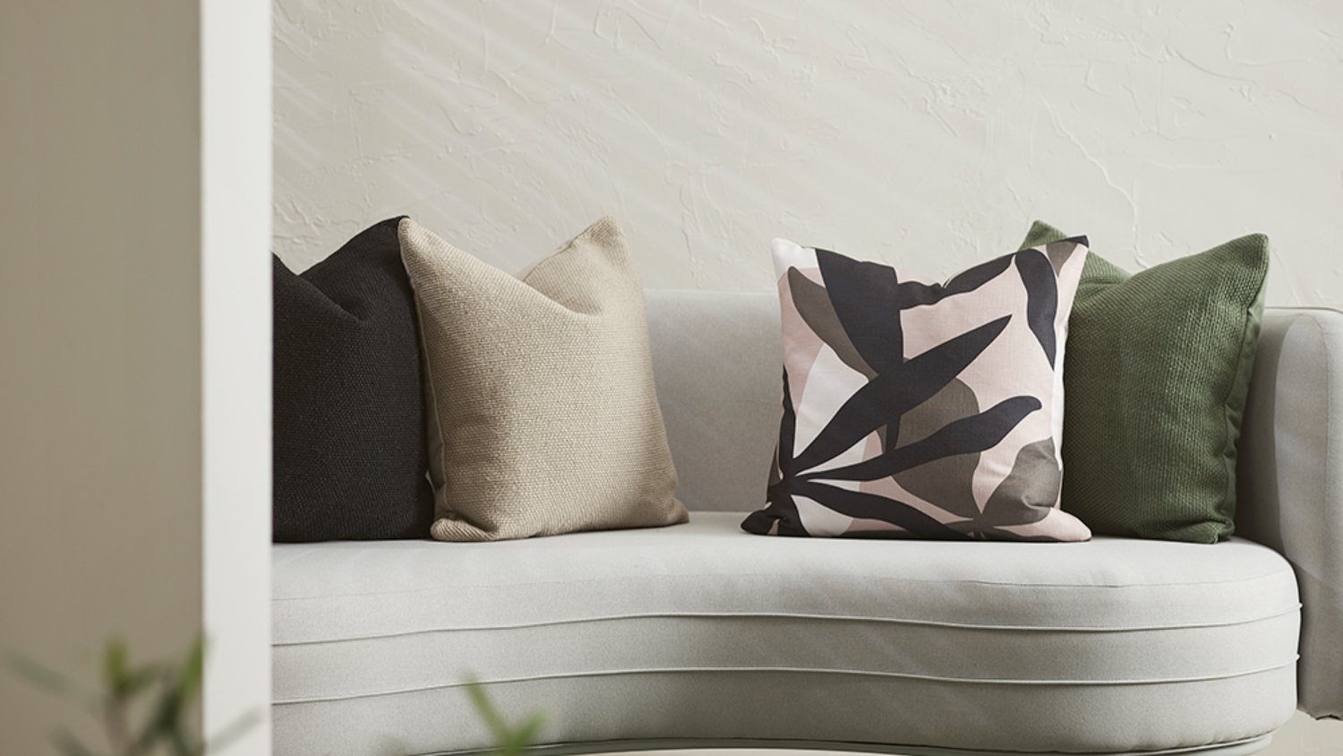 Close-up of beige sofa with green, beige, and abstract patterned cushions.