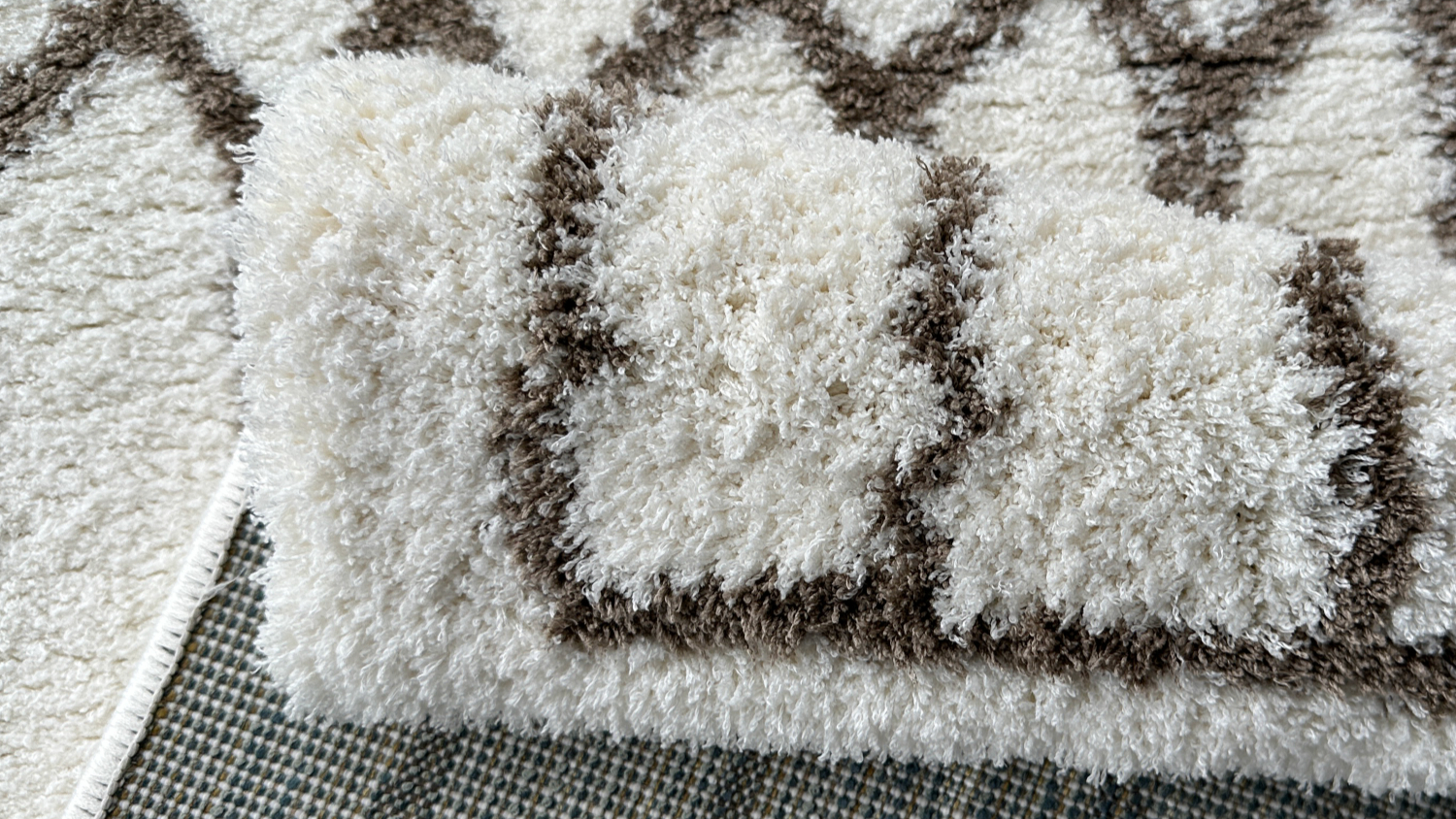 Folded white rug corner showing brown pattern and underside.
