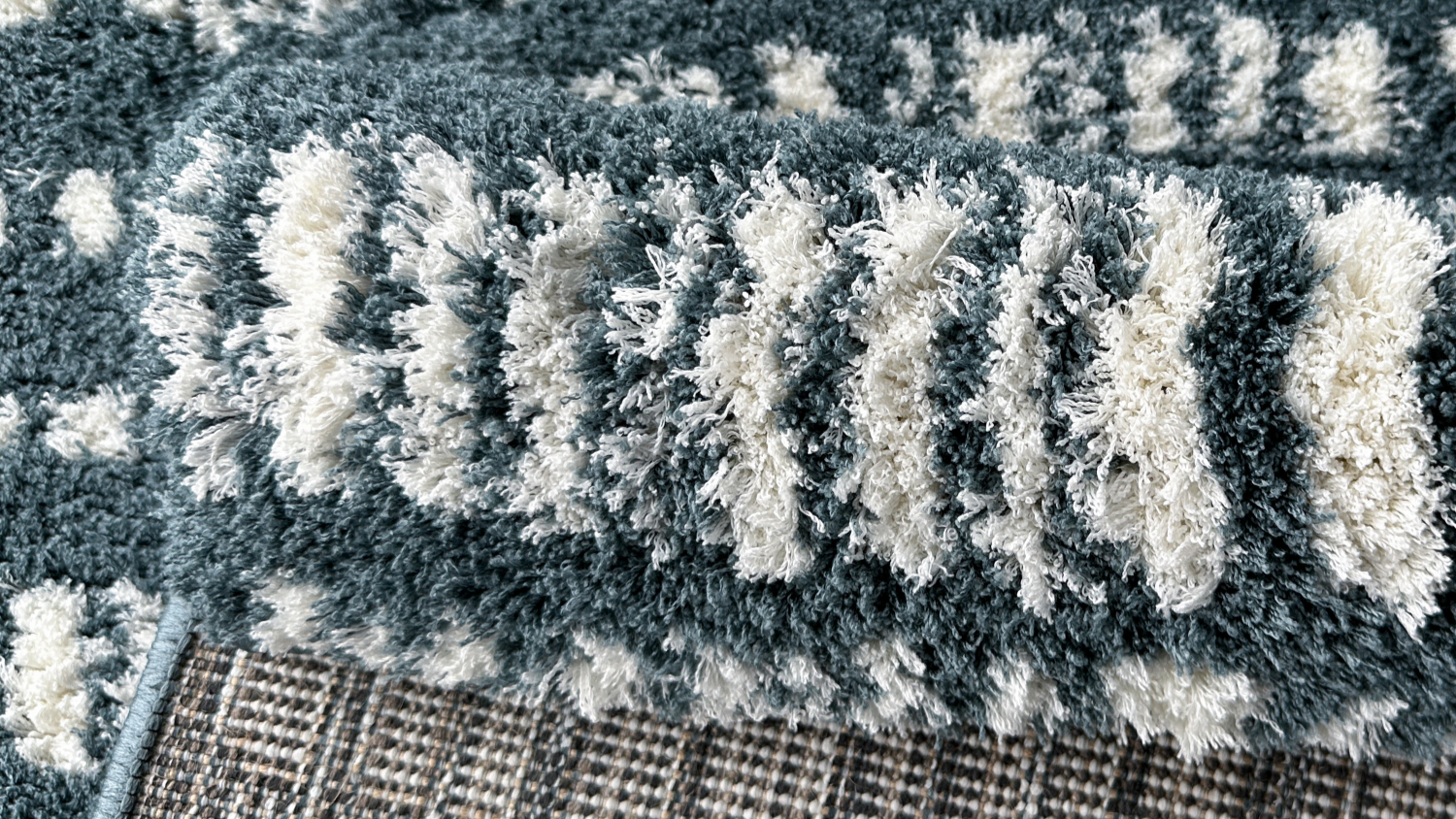 Folded corner view of blue and white striped rug, showing texture and underside detail.