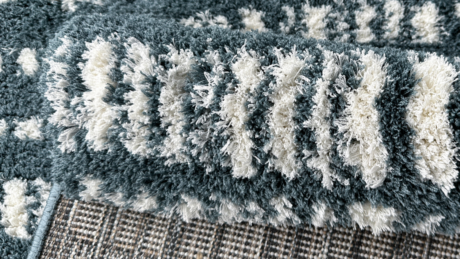 Folded corner view of blue and white striped rug, showing texture and underside detail.