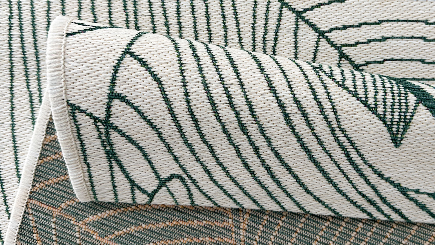 Emilia Monstera Outdoor Rug. Overlapping tropical green leaves with fine line details on ivory background, creating a layered green botanical pattern.