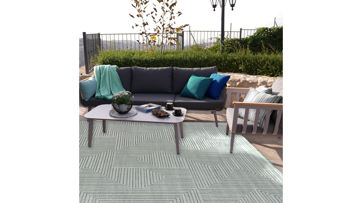 Porto Axis Outdoor Rug. A geometric pattern of nested right-angled lines forming square spirals in a grid layout, in ivory and green colours.