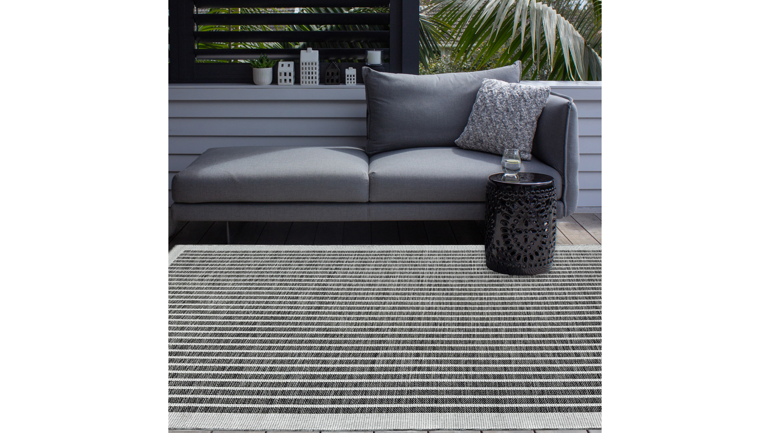 Porto Linha Outdoor Rug. Shows a vertical striped pattern with evenly spaced thin lines in black and gray tones, framed by a light border.