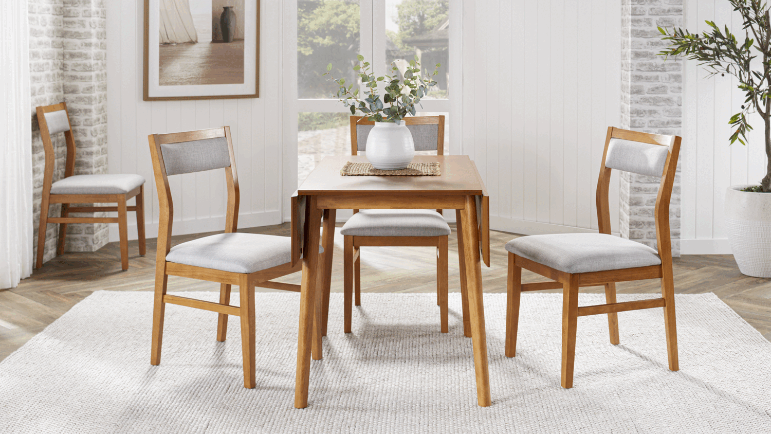 A wooden dining set arranged in a room with hardwood floors and a view of a green garden.