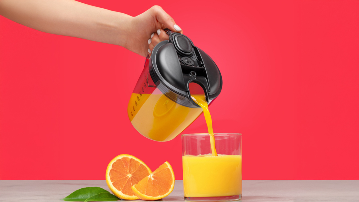 A person pouring fresh orange juice from a pitcher into a glass