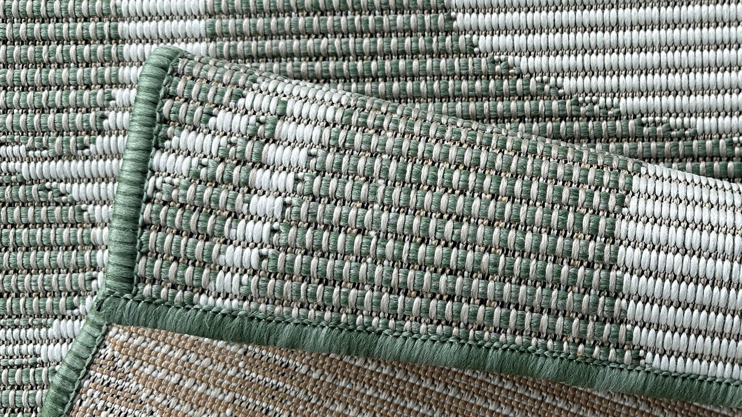 Porto Tropica Outdoor Rug. Large tropical single leaf design with bold curved segments, set against a fine line background.