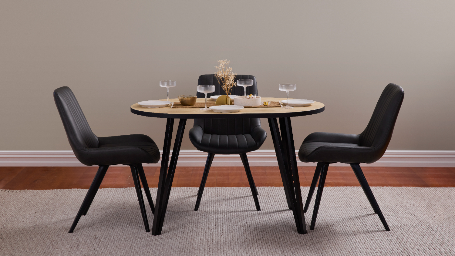 Round Orb 1200mm dining table in light wood finish, surrounded by three black chairs