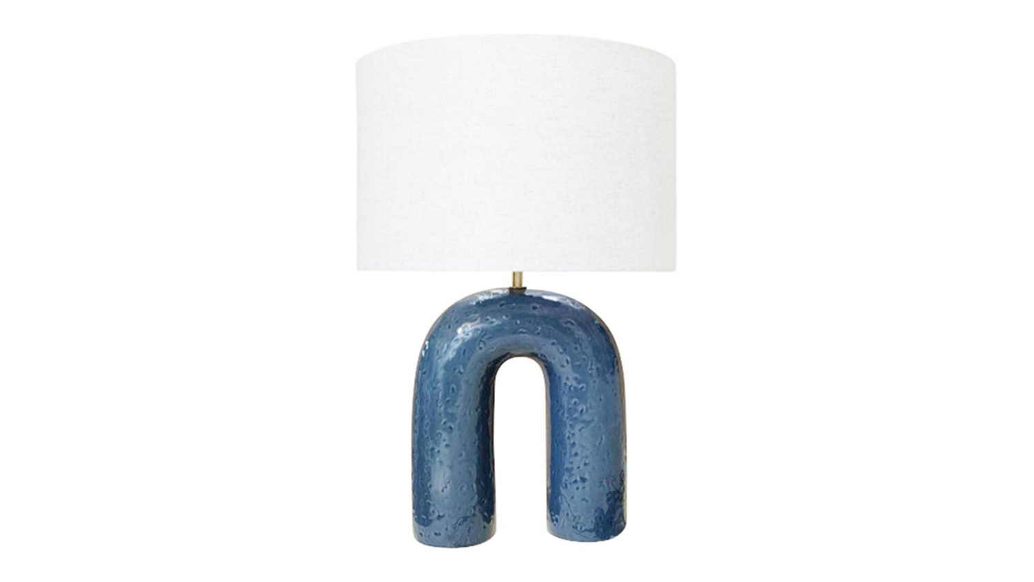 Modern ceramic table lamp with a unique U-shaped arch base in a deep blue glaze, topped with a white drum fabric shade