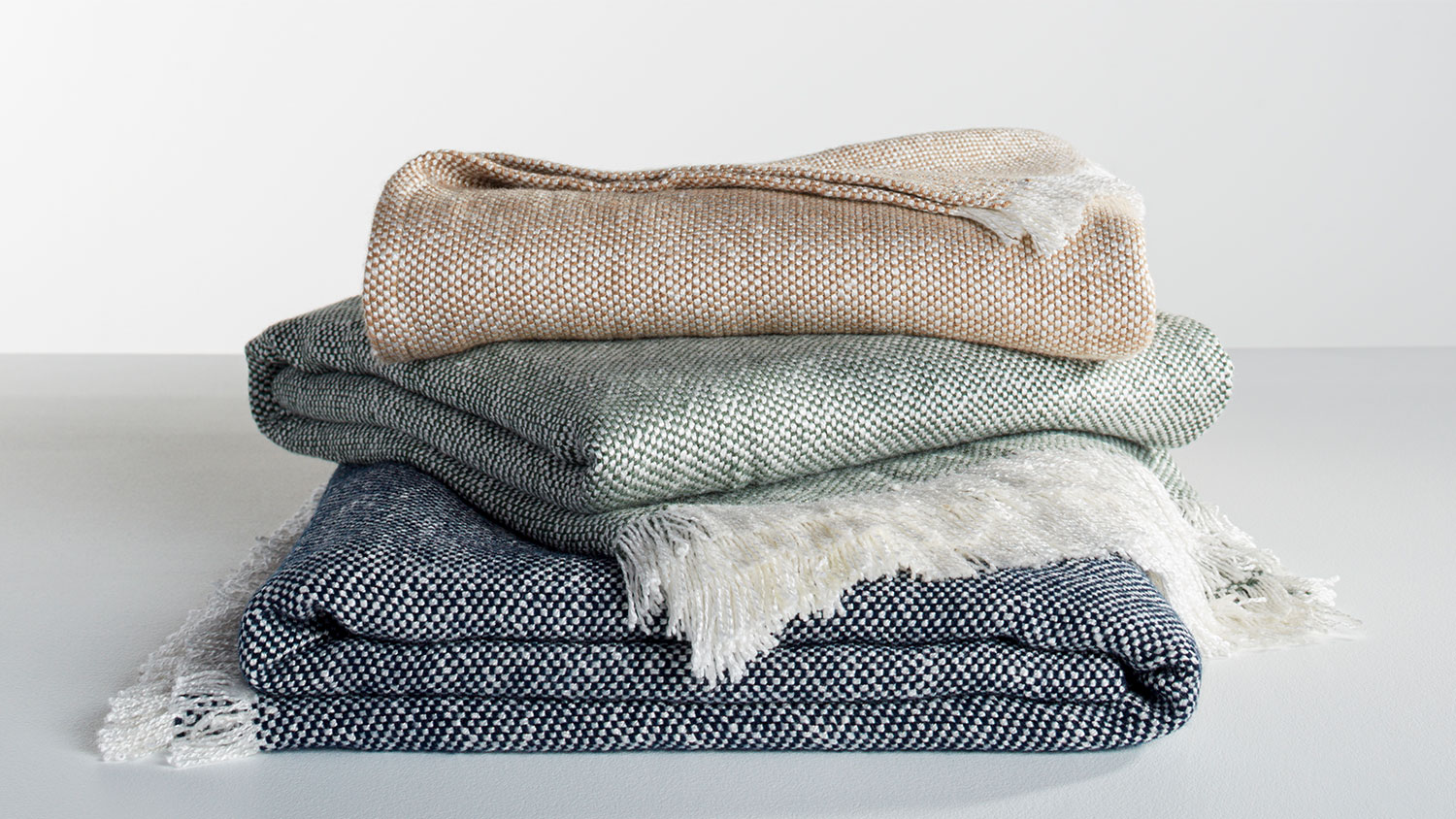 Denali Throw group shot showing Navy, Coffee and Dark Green throws stacked.