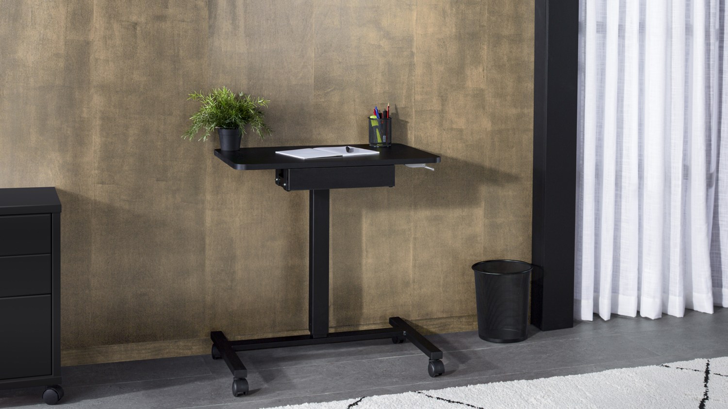 Black Shift Manual Standing Desk with a rectangular tabletop, adjustable height, and sturdy base on four castor wheels
