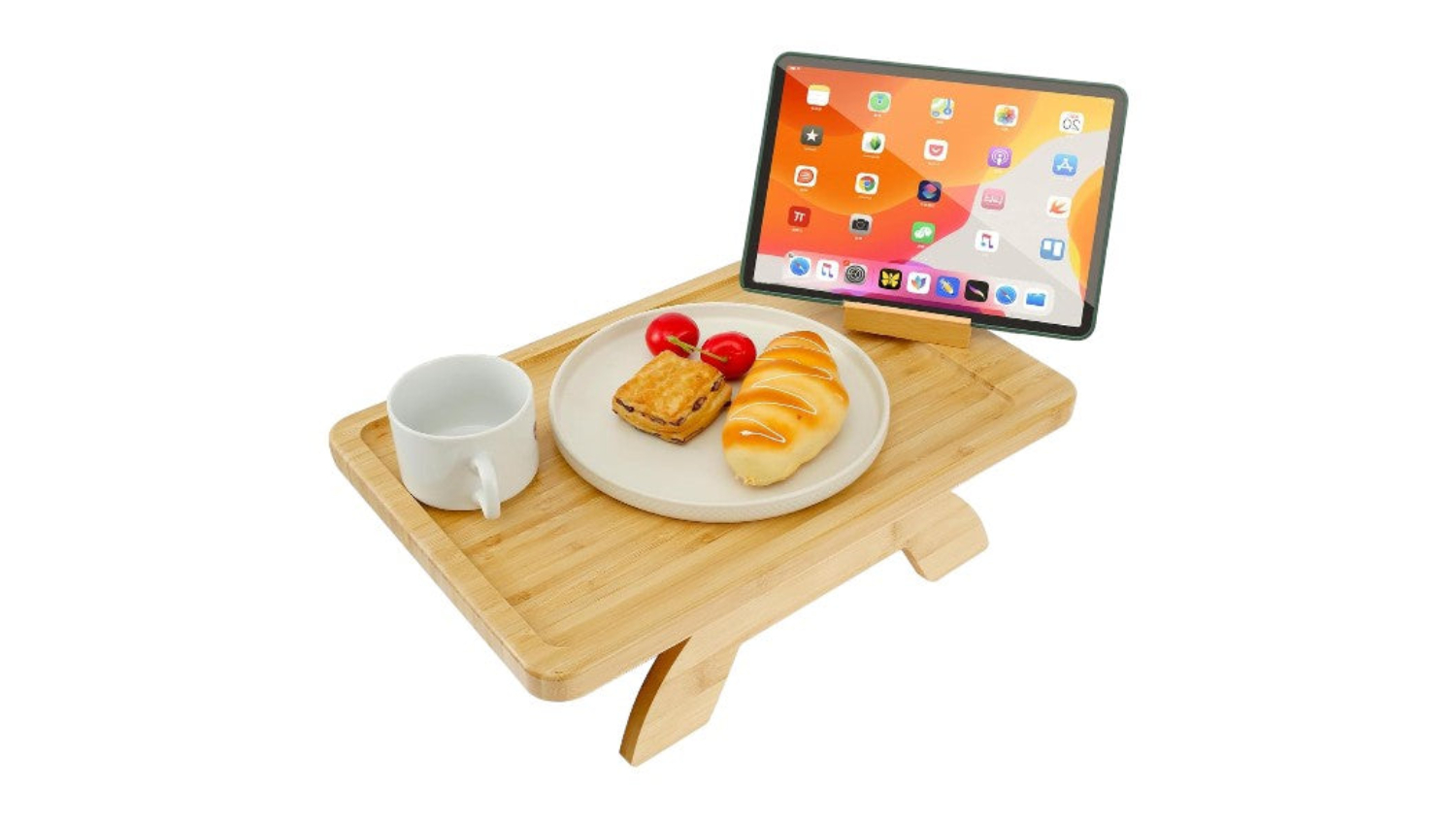 Bamboo couch arm table holding a plate of pastries, a coffee mug, and a tablet on a rotating holder