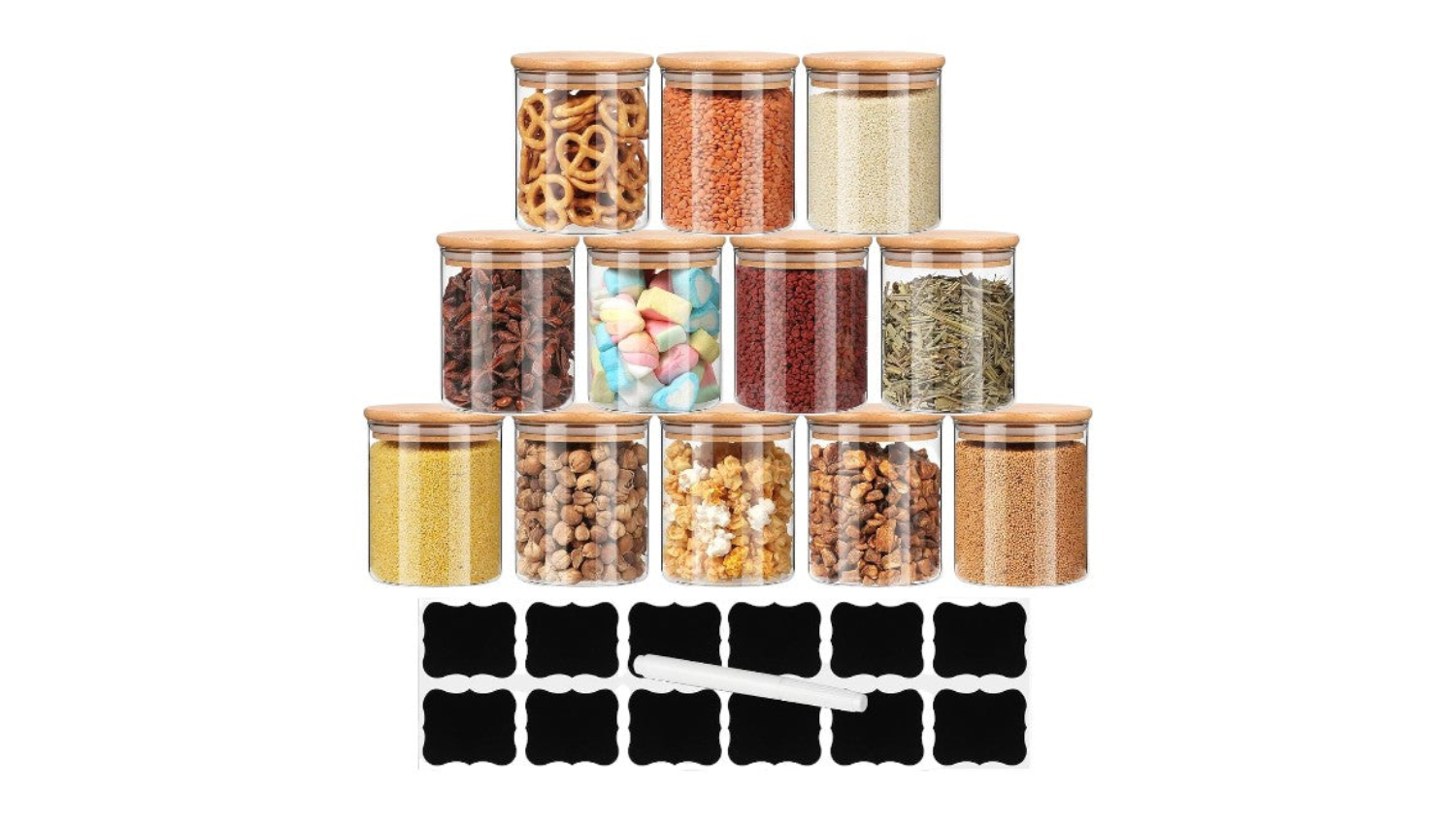 Four glass jars with bamboo lids and attached spoons filled with almonds, pasta, coffee beans, and oats